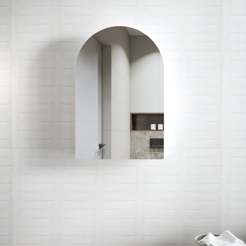 A matte white mirror cabinet with an arched design, installed in a bathroom with tile walls.